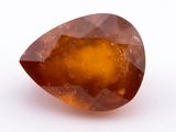 un gros plan d'un gros diamant orange sur une surface blanche
