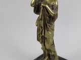 bronze statue of a woman holding a bird on a marble base