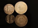four different types of silver coins on a black surface