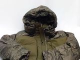 une image représentant une veste et un sac de couchage posés sur une surface blanche