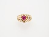 a yellow gold ring set with a pear shaped ruby and diamonds