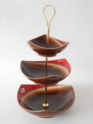 three tiered serving tray with a gold handle and a red and black design
