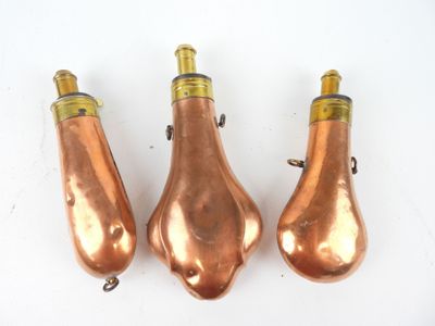trois lampes de couleur cuivrée posées sur une surface blanche