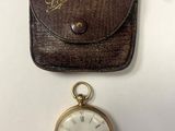 une vieille montre de poche, avec un étui en cuir à côté