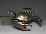 une image représentant une sculpture métallique représentant un crabe posée sur une surface grise