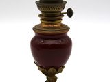 un vase rouge et doré posé sur une surface blanche