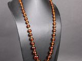 un collier composé de perles de verre orange, présenté sur un mannequin