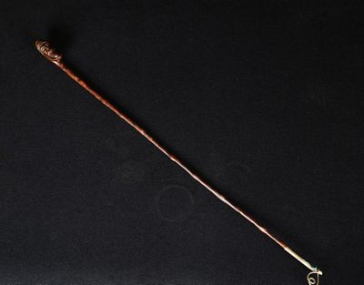 un vieux bâton en bois muni d'un manche en métal, sur fond noir