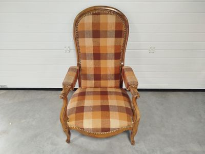 une vieille chaise dont le dossier et les accoudoirs sont recouverts d'un tissu à carreaux
