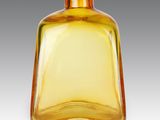 une bouteille en verre jaune avec un bouchon doré, posée sur une surface blanche