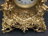 a gold clock with angels on it sitting on a table