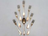 six fourchettes et une cuillère disposées en cercle sur une table