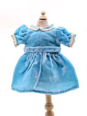 robe bleue pour une poupée posée sur un socle en bois, sur fond blanc