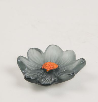 une petite fleur grise avec un cœur orange sur un fond blanc