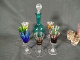 several different colored wine glasses and a bottle on a table