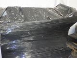 un gros tas de film plastique noir posé sur une pile de cartons