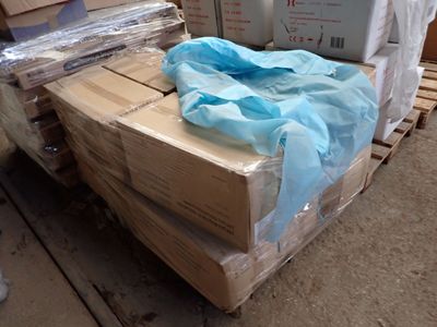 une pile de cartons posée sur une palette, surmontée d'un sac bleu