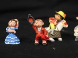 five figurines of different people on a black background
