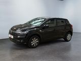 Une voiture noire est garée dans une grande pièce aux murs blancs.