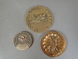 two gold coins and a silver coin on a white surface