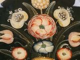 a black plate with a painting of flowers on it