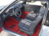 the interior of a car with red carpeting and black leather seats