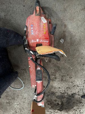 une tondeuse de couleur terre rouge posée par terre à côté d'une chaise noire