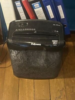 a paper shredder sitting on the floor next to a stack of folders