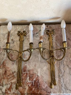 three brass wall sconces mounted on a marble wall in a room