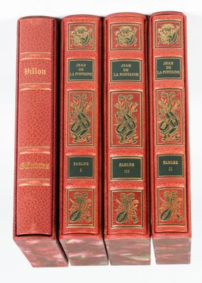 quatre livres rouges sont alignés sur une surface blanche