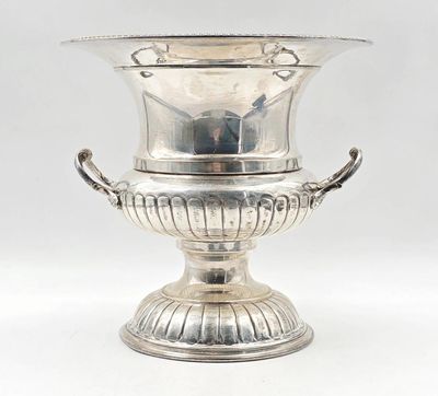une coupe ancienne en métal argenté, munie d'anses et posée sur un socle