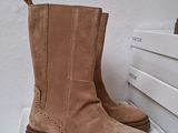 tan sued boots on display in front of a white wall