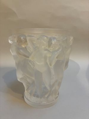 un vase en verre orné d'une statuette, posé sur une table