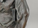 statue of a man with a hat and a robe holding a book
