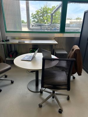 un bureau sur lequel se trouve un ordinateur portable, avec une chaise devant