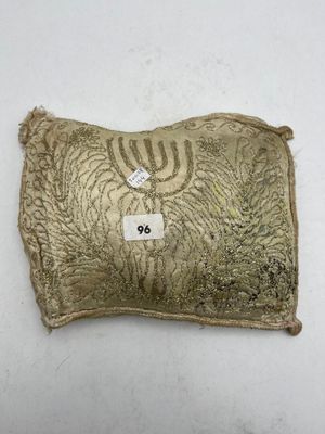 a gold pillow with a menorah on it on a white surface