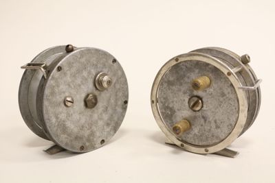 two small metal reels sitting on a white surface