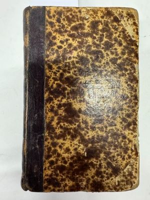 un vieux livre à la couverture brune posé sur une surface blanche