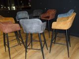four different colored barstools sitting on a wooden floor