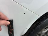 someone is measuring the width of a white car with a ruler