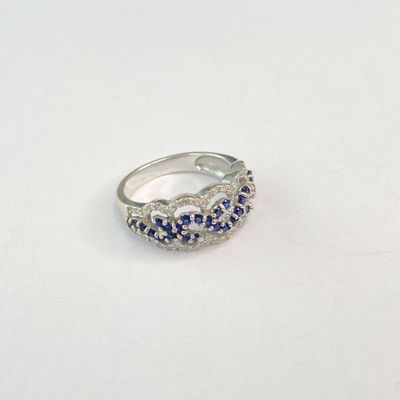 une image représentant une bague ornée de pierres bleues et blanches sur un fond blanc