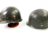 pair of wwii german steel helmets on stand on white background