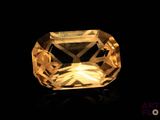 a close up of a yellow sapphire stone on a black surface