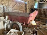 a red wagon sitting in the middle of a barn filled with sheep