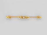 une broche en forme de lingot d'or ornée de fleurs et de feuilles