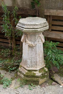 une statue en pierre trônant au milieu d'un jardin