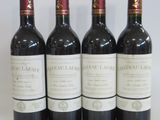 four bottles of wine are lined up on a white surface