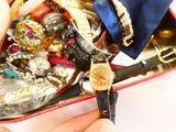 une personne tenant une montre dans un coffret rempli d'objets divers