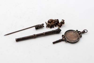 un petit objet métallique et un autre petit objet métallique posés sur une surface blanche