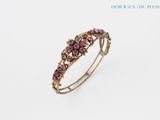 a close up of a ring with purple stones on a white background